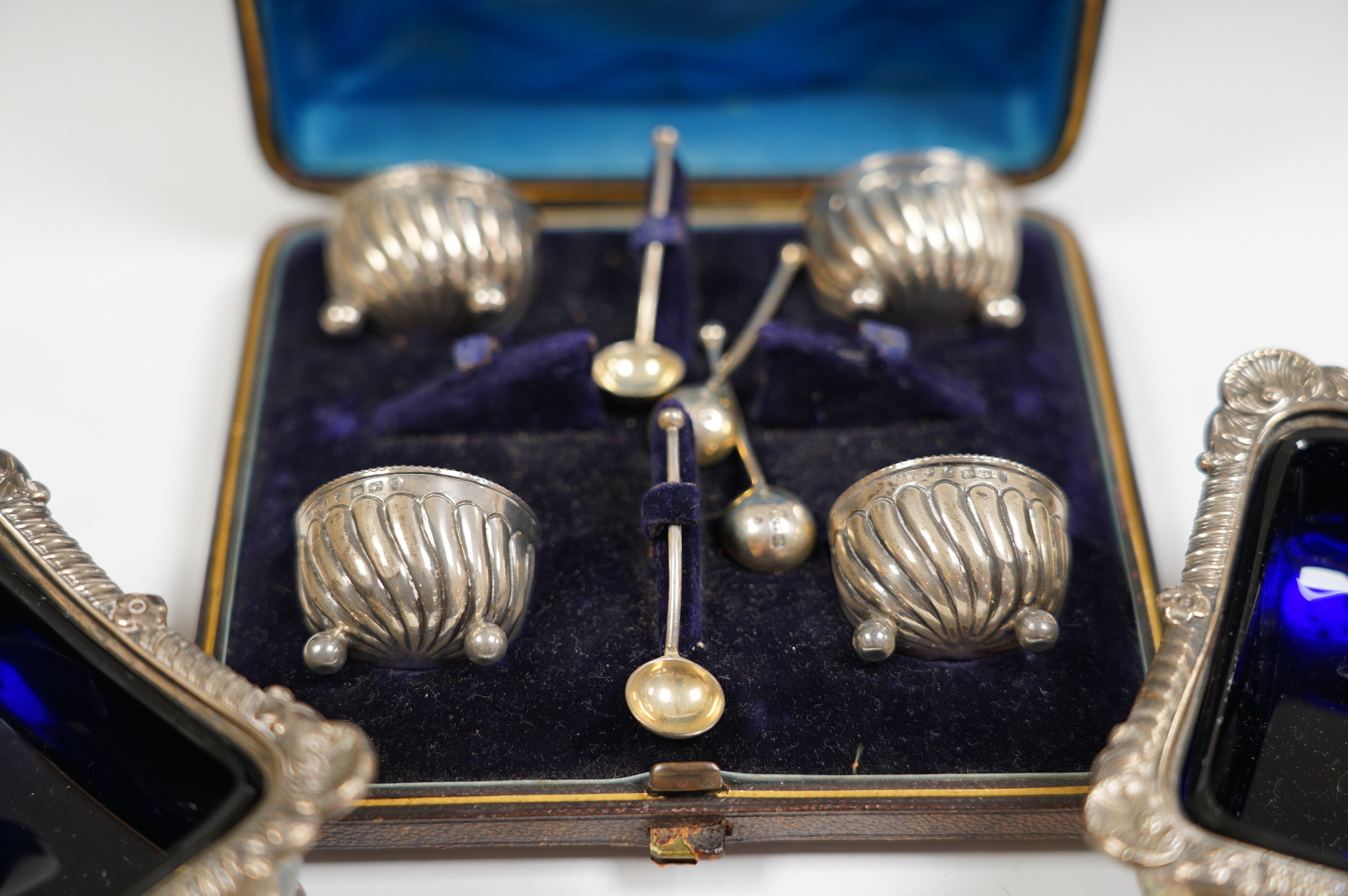 A pair of late Victorian silver rectangular salts, Hawksworth, Eyre & Co, London, 1897, 91mm with blue glass liners and a cased set of four Victorian silver tub salts with spoons. Condition - fair